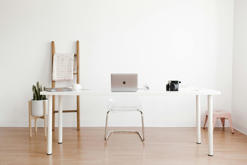 Minimalistisch leben – mehr Klarheit Bright and minimalist home office setup with a white desk, laptop, and potted plant.
